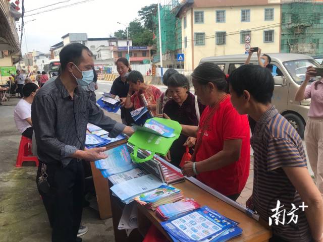 九陂鎮(zhèn)人大主席黃成志（左一）給群眾派發(fā)法治宣傳單和環(huán)保袋。